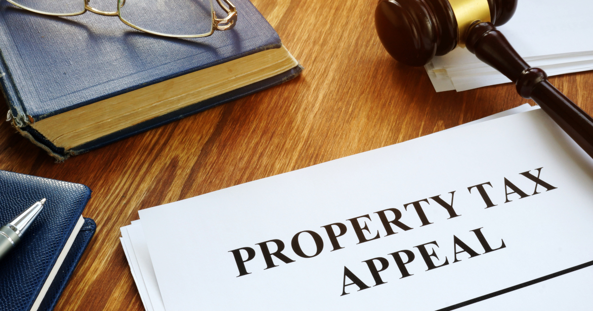 A Document Titled Property Tax Appeal And A Gavel, Along With A Law Book And A Pair Of Reading Glasses, On A  Desk