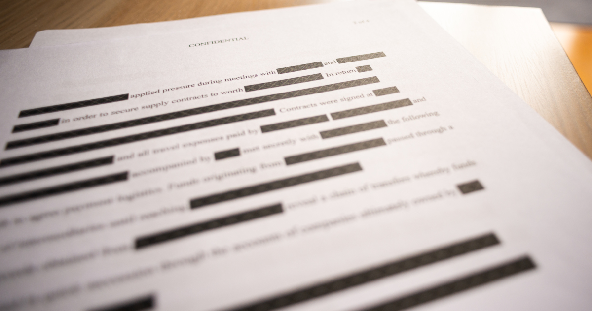 A Heavily Redacted Document With The Word Confidential Typed Across The Top