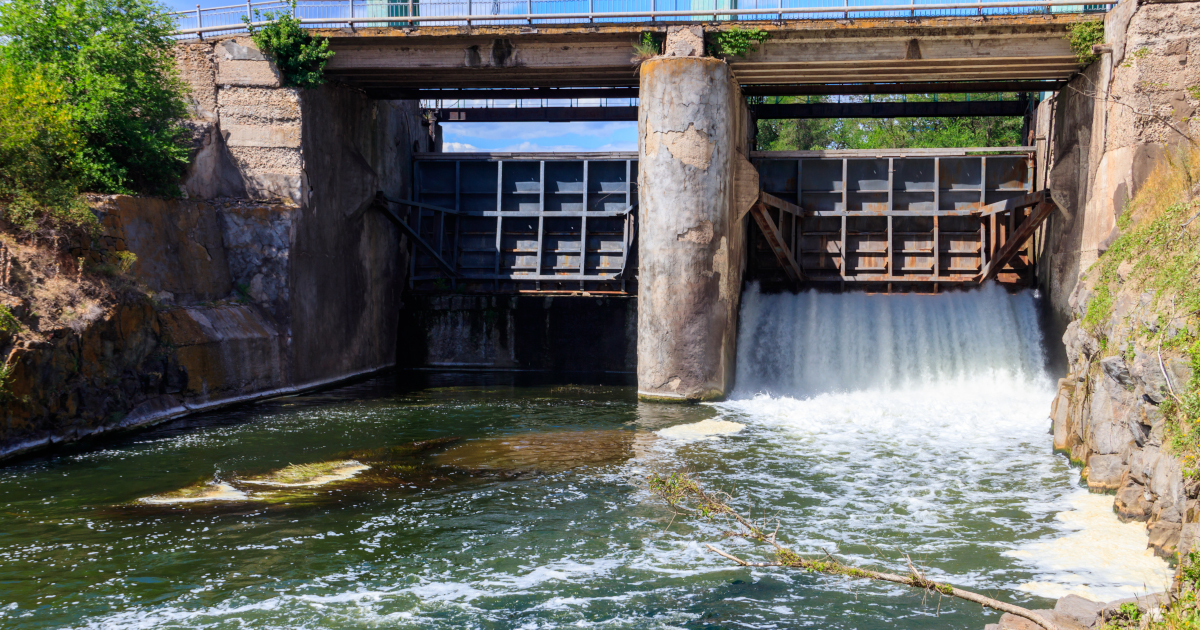 A Two-gated Gravity Dam With One Gate Open On A Summer Day