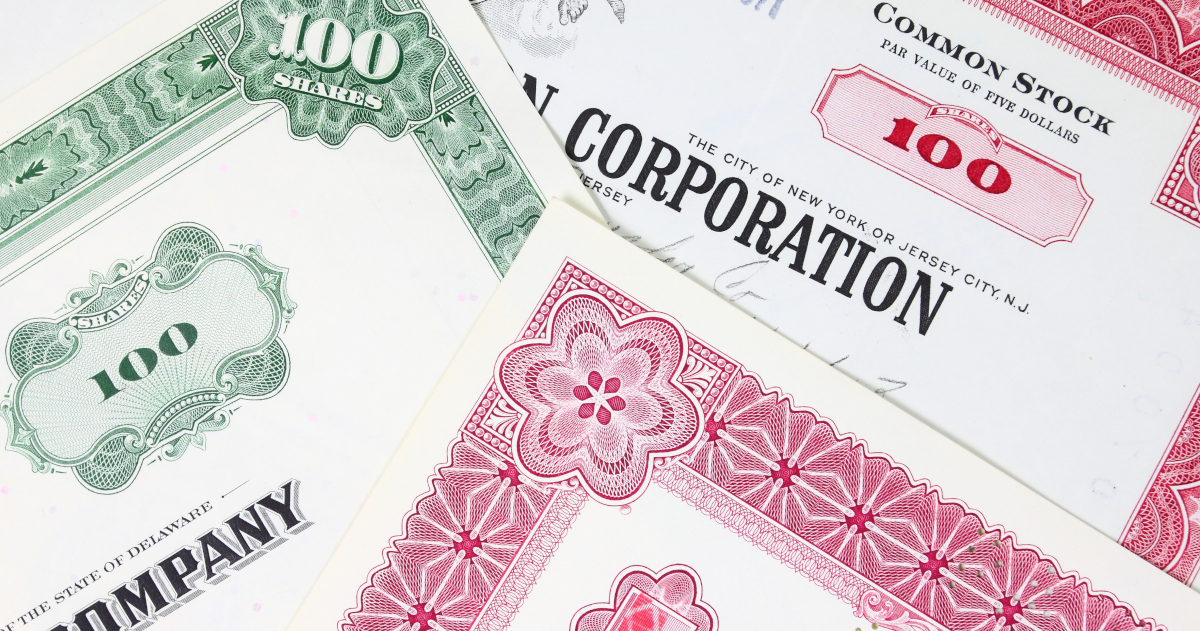 Three Corporate Stock Certificates Lying Atop Each Other At Angles, Some Printed In Red Ink And Blank Ink, Some Printed In Green Ink and Black Ink