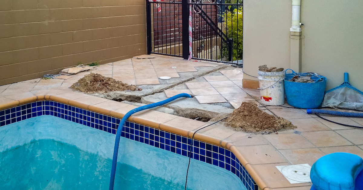 A View Of One End Of A Medium-Sized Swimming Pool, Drained Of Water, With Two Holes Chieseled Out Of The Concrete Near The Edge Of The Pool