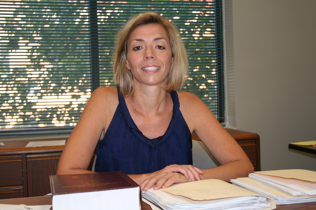 A woman smiling and sitting at a desk