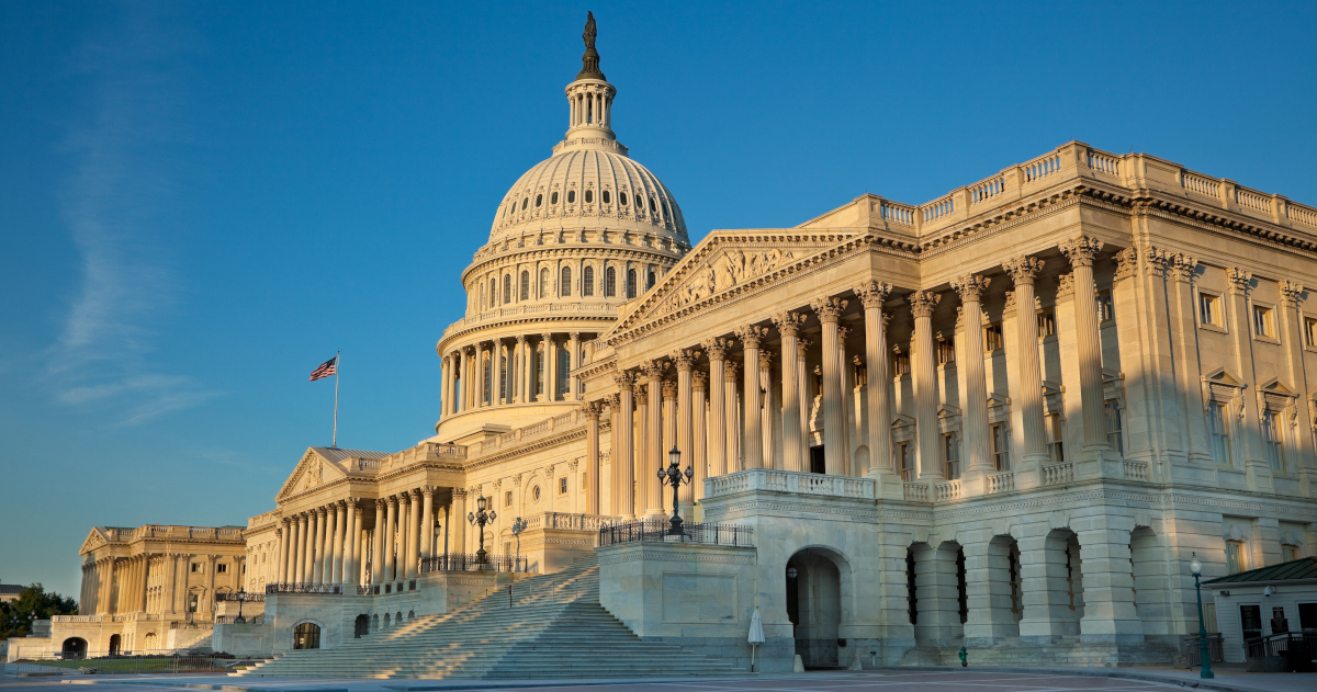 The United States Captiol, Yellowed By The Late Afternoon Sun, Seen From an Angle Against A Clear Blue Sky