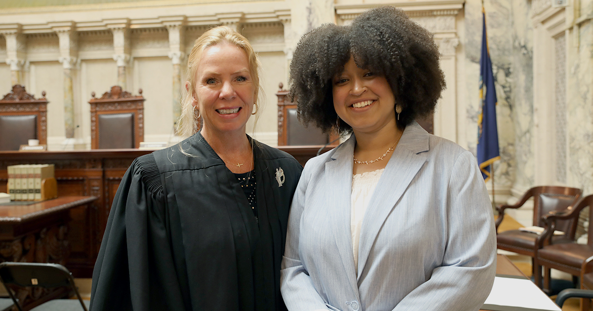 two people stand and smile at the camera