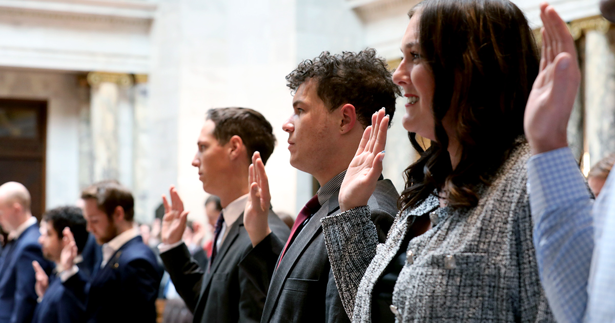 several people stand with hands raised to take an oath