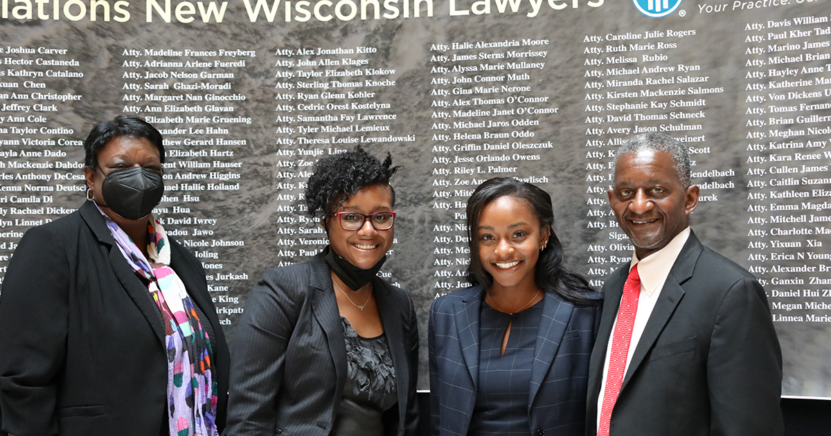 Four family members stand in front of a sign listing names of new lawyers