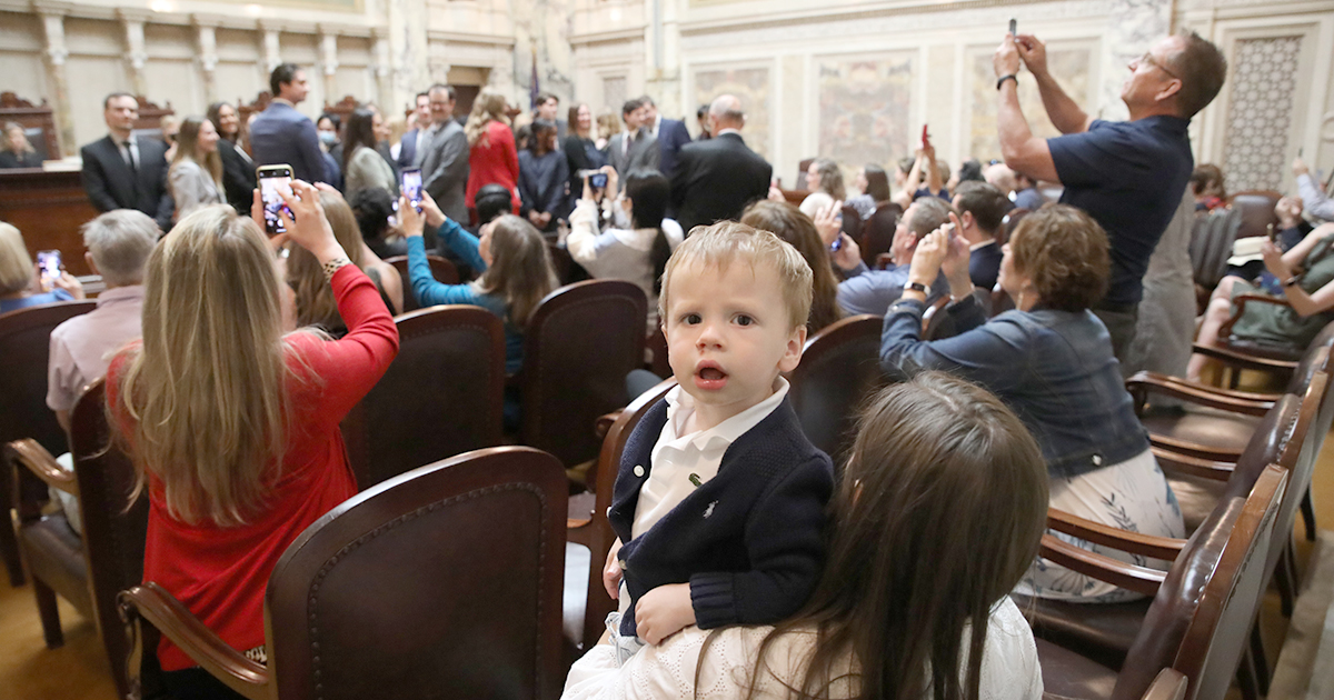 young boy looks at the camera in a crowded Supreme Court Hearing Room