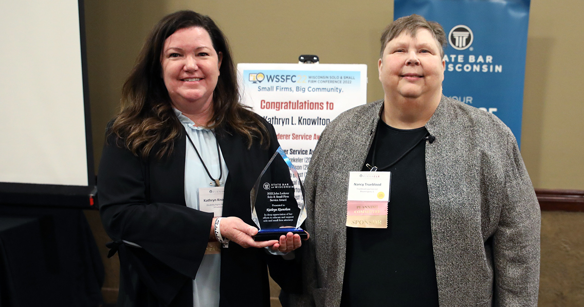 two people smiling at the camera with one holding an award