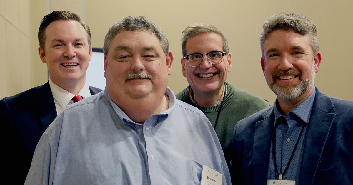 Four men smile at the camera