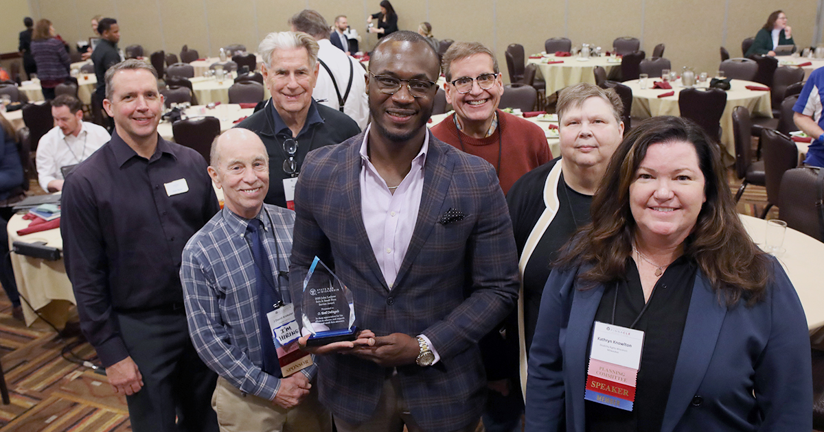 Smiling group of people with center person holding an award