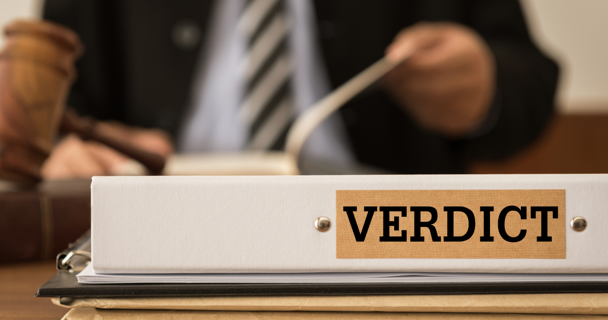 Binder Labeled Verdict On A Table With A Judge And Gavel In The Background