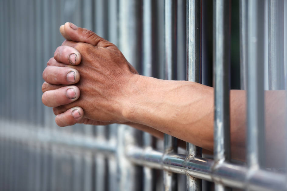 Prisoners hands on jail cell bars