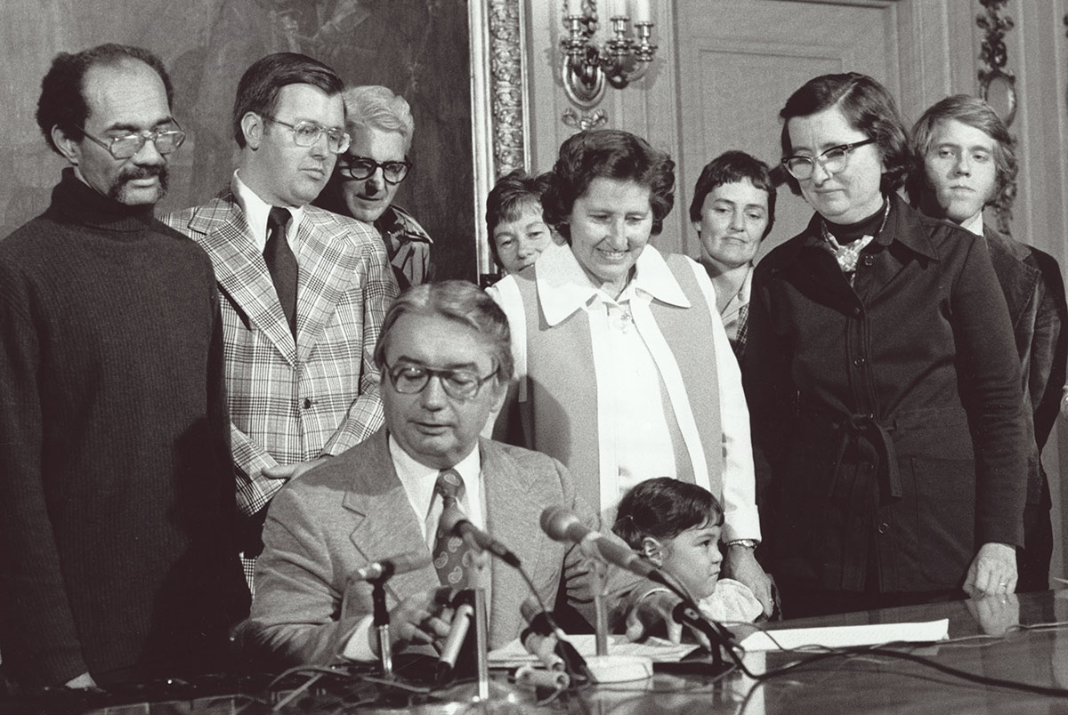 Governor Patrick Lucey, seated at desk, signs the Equal Rights Amendment