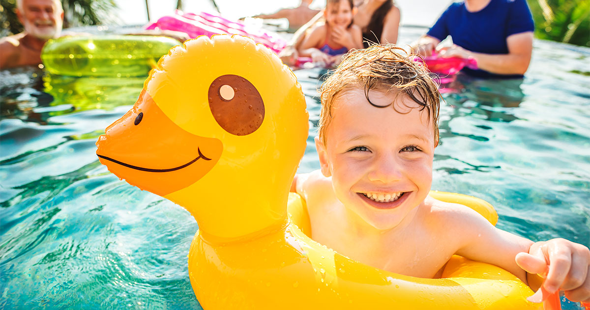 child playing in a pool while parents smile
