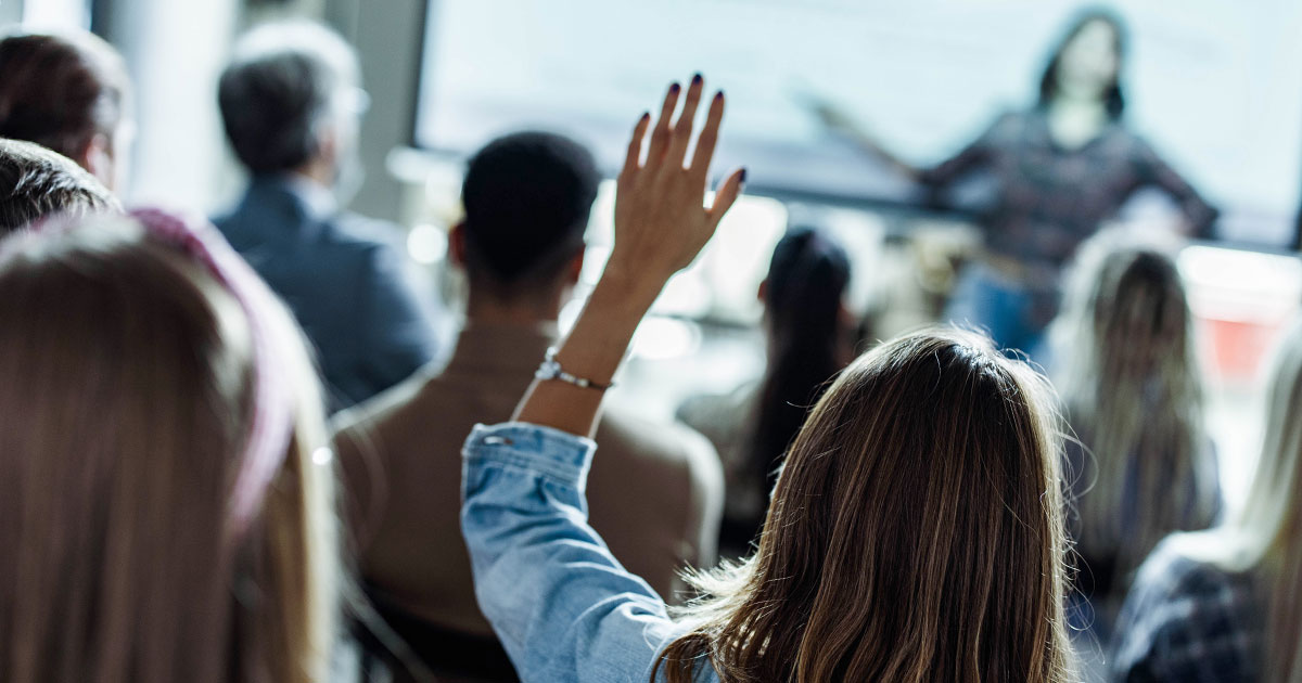 person raising their hand at a conference