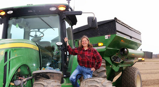 Roberta Heckes with a piece of John Deer farm equipment.