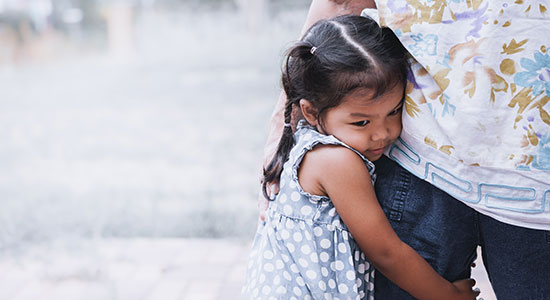 little girl hugs leg of adult