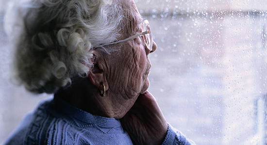 elderly woman stares out window