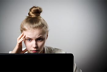 woman at laptop looks concerned