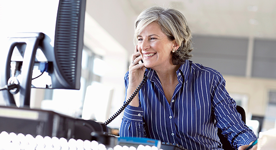 middle aged business woman takes phone call at desk