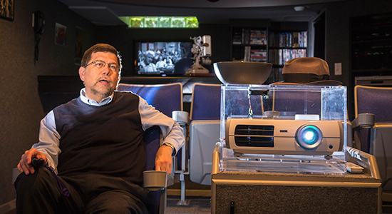 Fran Deisinger sits beside a film projector