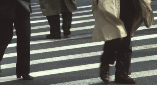 businessmen in trech coats cross street