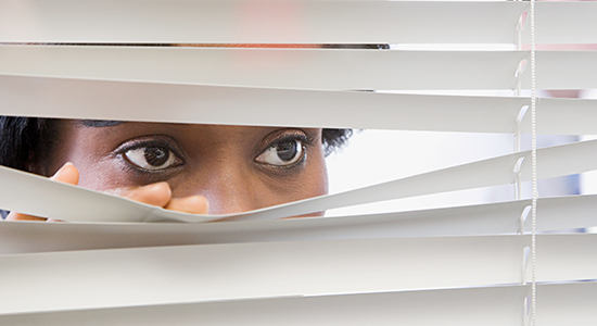 woman peeks through blinds