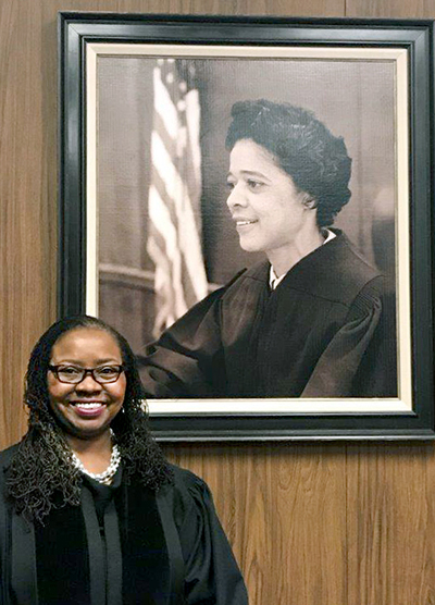 Chief Judge Maxine White, standing near her portait of Vel Phillips from 1971