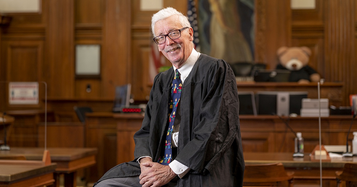 Christopher Foley sits in his courtroom. Behind him a teddy bear is visible on his bench