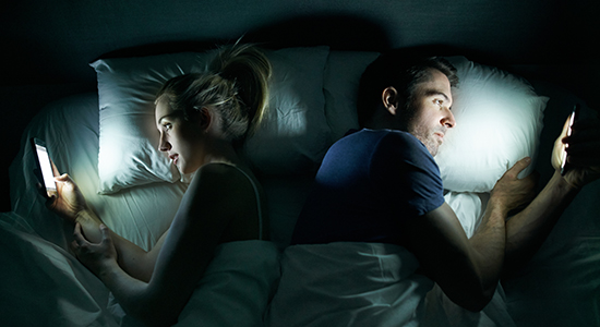 couple in bed looking at phones